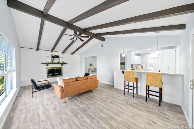 living room with light hardwood / wood-style floors, vaulted ceiling with beams, and ceiling fan