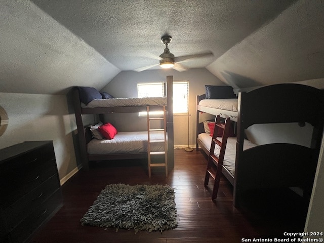 bedroom with ceiling fan, vaulted ceiling, dark hardwood / wood-style floors, and a textured ceiling