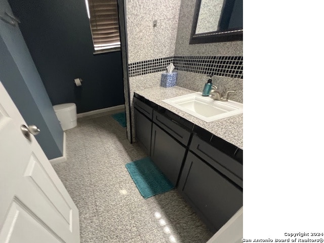 bathroom with vanity, toilet, and decorative backsplash