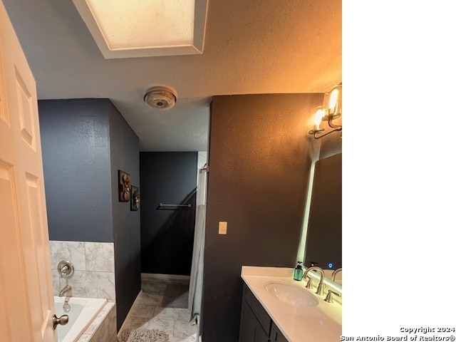 bathroom featuring vanity and a relaxing tiled tub