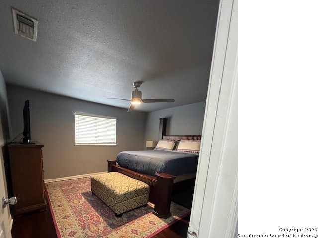 bedroom featuring dark wood-type flooring, a textured ceiling, and ceiling fan