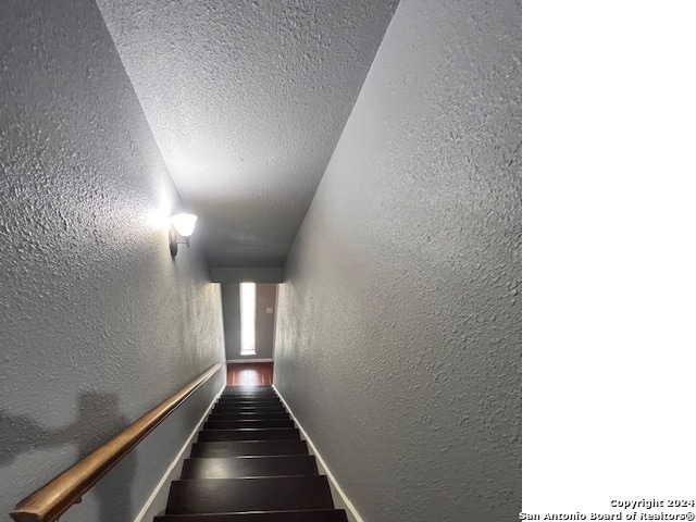 staircase featuring a textured ceiling