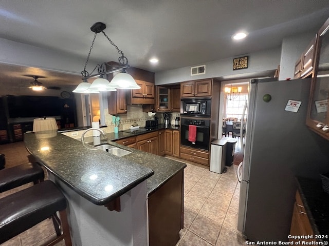 kitchen featuring a kitchen bar, kitchen peninsula, black appliances, and pendant lighting