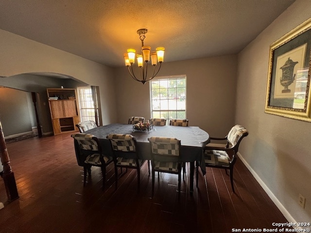 dining area with dark hardwood / wood-style flooring, a notable chandelier, and a textured ceiling