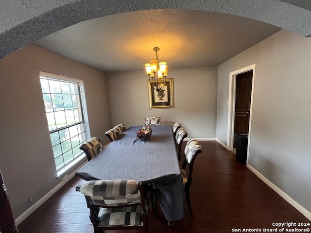 dining area with a chandelier, a textured ceiling, and dark hardwood / wood-style floors