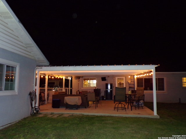 back house at night featuring a patio area