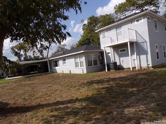 rear view of house with central AC unit, a balcony, and a carport