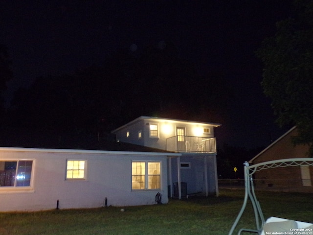 back house at twilight with a lawn and a balcony