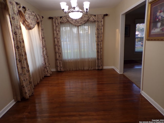 unfurnished dining area featuring dark wood-type flooring and a chandelier