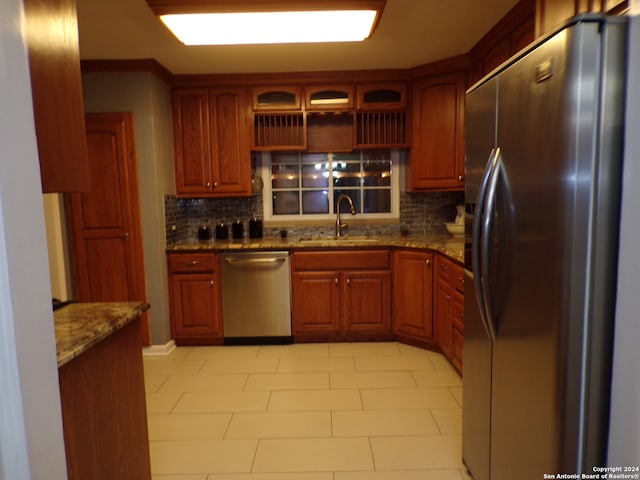 kitchen featuring decorative backsplash, appliances with stainless steel finishes, sink, and stone counters