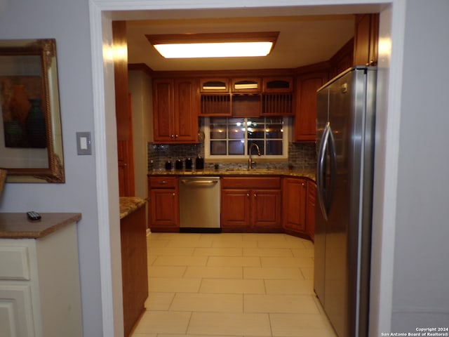 kitchen with stainless steel appliances, sink, tasteful backsplash, and dark stone countertops