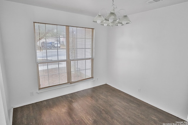 empty room with dark hardwood / wood-style floors and a notable chandelier