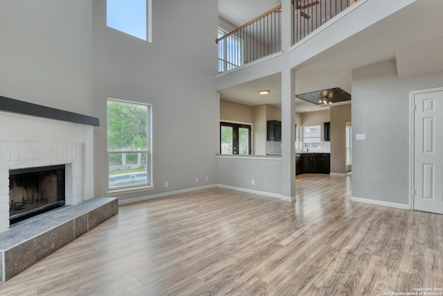 unfurnished living room featuring a high ceiling, ceiling fan, and light hardwood / wood-style floors