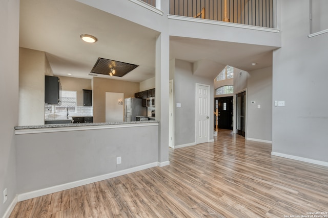 kitchen with tasteful backsplash, kitchen peninsula, light hardwood / wood-style floors, and stainless steel appliances