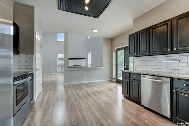 kitchen with light hardwood / wood-style flooring, tasteful backsplash, light stone counters, and stainless steel appliances