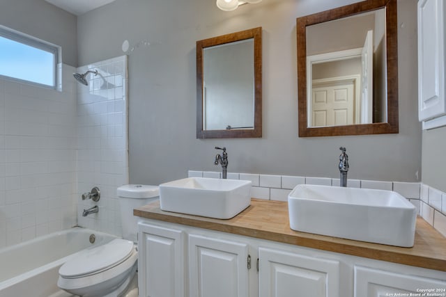 full bathroom featuring tiled shower / bath, toilet, and vanity