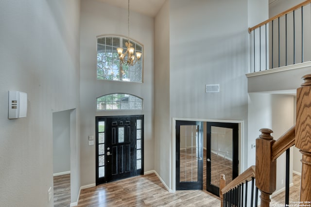 foyer entrance with a high ceiling, an inviting chandelier, and light wood-type flooring