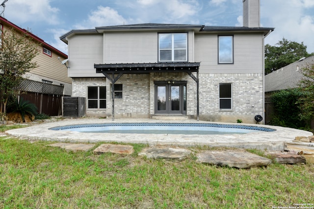 rear view of house with a lawn and french doors