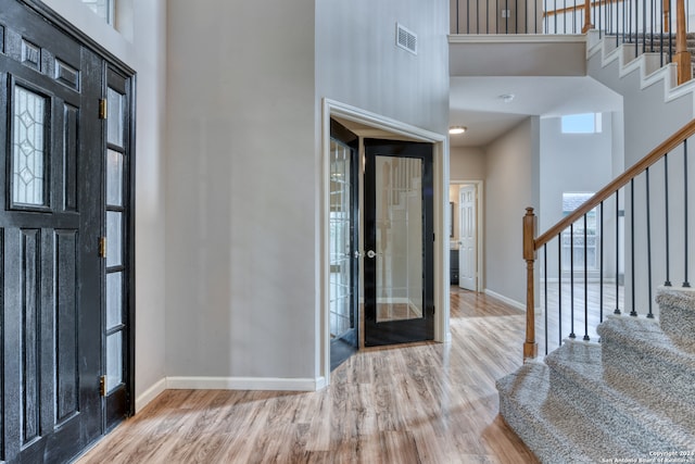 foyer entrance featuring light hardwood / wood-style flooring and a high ceiling