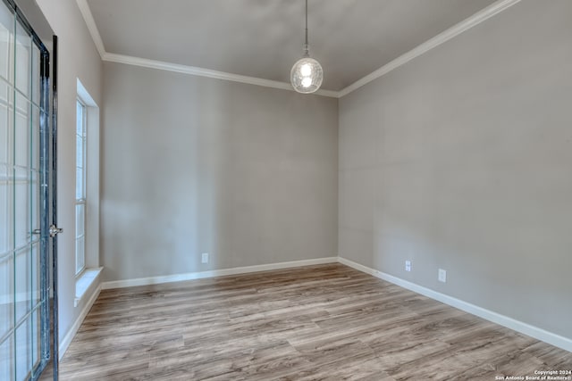 spare room featuring light wood-type flooring and crown molding