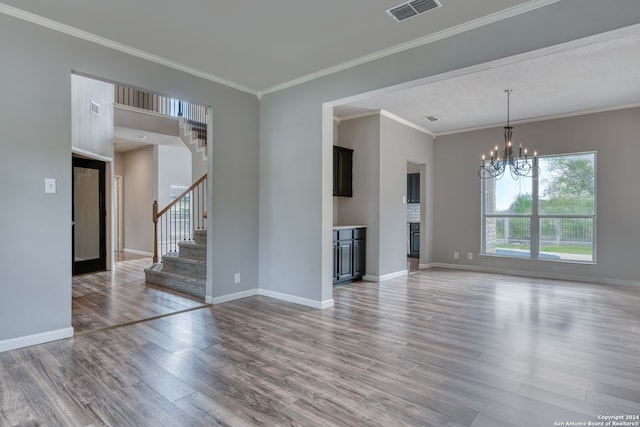 unfurnished living room with an inviting chandelier, light hardwood / wood-style flooring, and crown molding