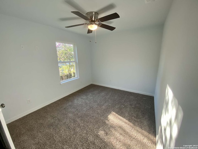 empty room featuring ceiling fan and dark colored carpet