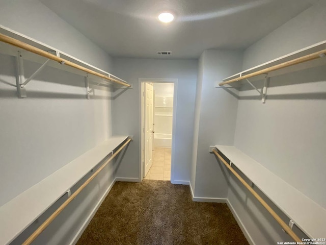 walk in closet with dark colored carpet