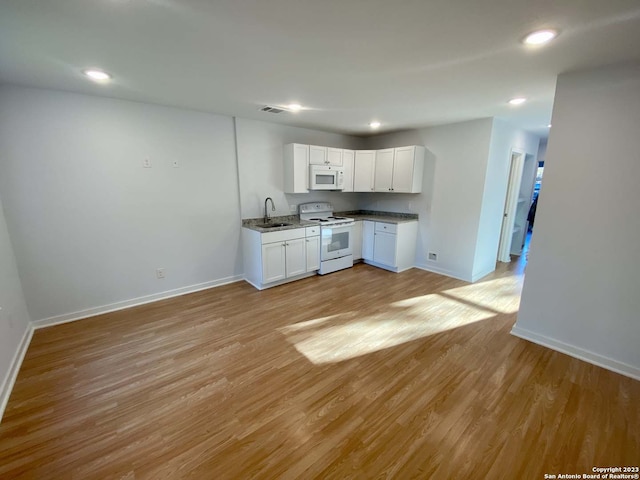 kitchen with white cabinets, light wood-type flooring, sink, and white appliances