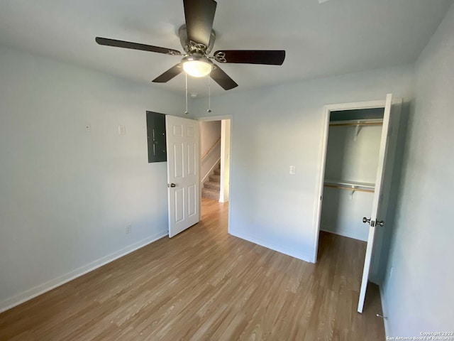 unfurnished bedroom featuring electric panel, ceiling fan, a closet, and light hardwood / wood-style flooring