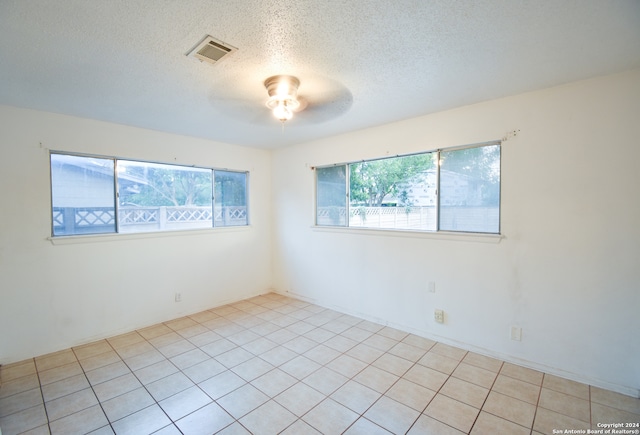 unfurnished room featuring a healthy amount of sunlight, light tile patterned floors, and a textured ceiling