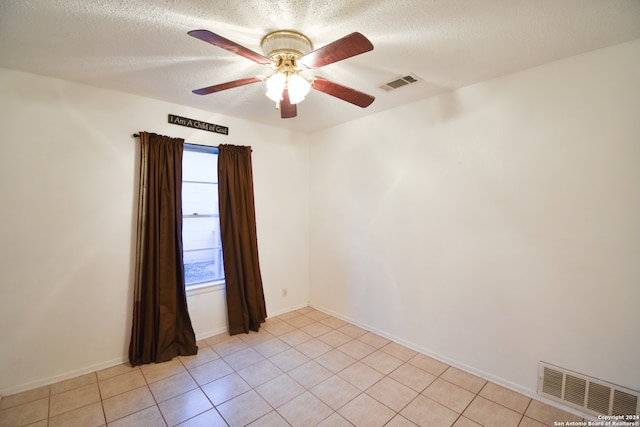 tiled spare room featuring a textured ceiling and ceiling fan