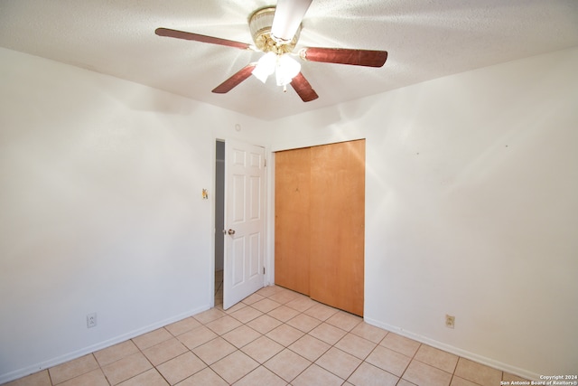 tiled empty room featuring ceiling fan and a textured ceiling