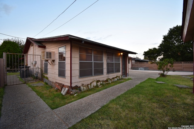 view of side of property featuring a wall mounted AC and a yard