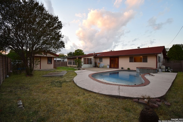 back of property with a shed, a lawn, a fenced in pool, and a patio area