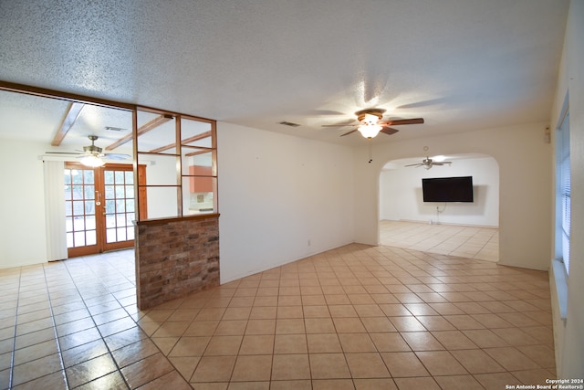 tiled empty room with french doors and a textured ceiling