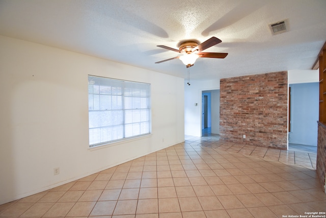 empty room featuring a textured ceiling, ceiling fan, and light tile patterned floors