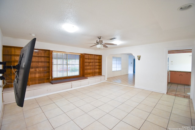 unfurnished room featuring ceiling fan, a textured ceiling, light tile patterned floors, and a healthy amount of sunlight