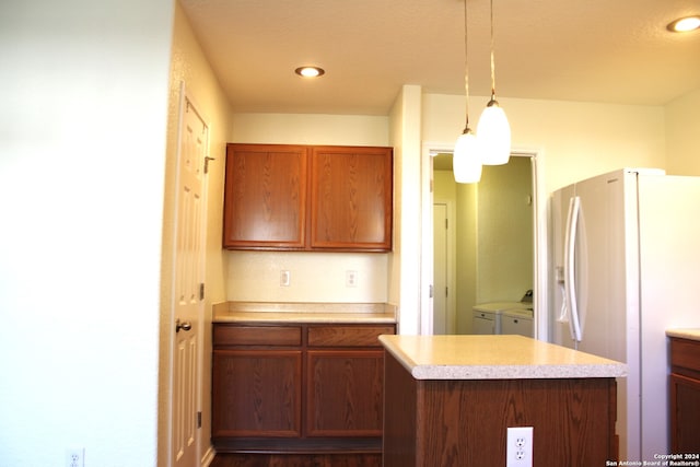 kitchen with pendant lighting, washing machine and dryer, and white refrigerator with ice dispenser