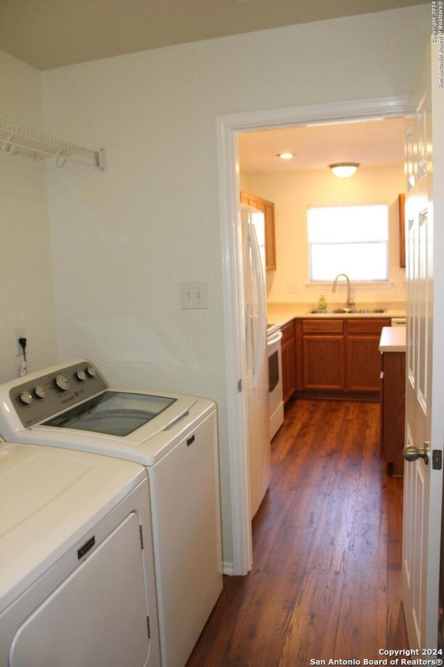 clothes washing area with dark wood-type flooring, independent washer and dryer, and sink