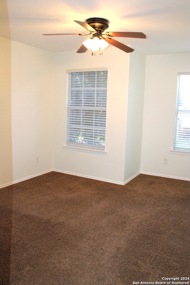 spare room featuring dark carpet and ceiling fan