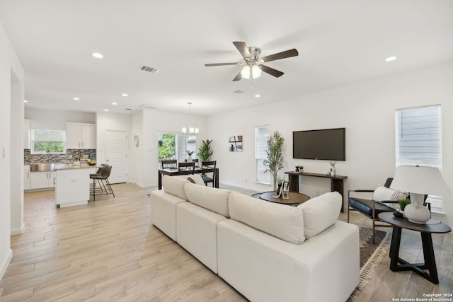 living room featuring light hardwood / wood-style floors and ceiling fan with notable chandelier