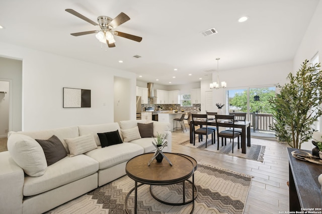 living room featuring light hardwood / wood-style floors and ceiling fan with notable chandelier