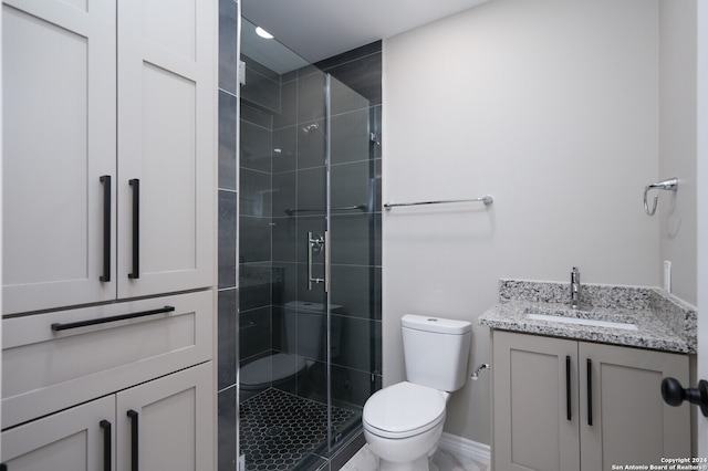 bathroom with tiled shower, vanity, and toilet