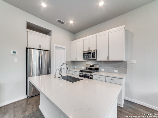 kitchen featuring stainless steel appliances, sink, tasteful backsplash, an island with sink, and white cabinets