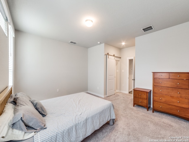 bedroom with light carpet and a barn door