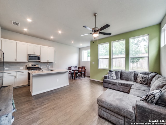 living room featuring sink, a wealth of natural light, wood-type flooring, and ceiling fan