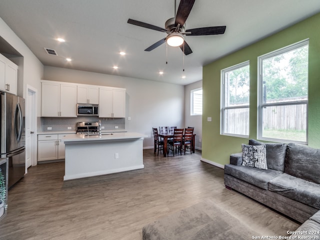 kitchen featuring stainless steel appliances, white cabinetry, a center island with sink, ceiling fan, and hardwood / wood-style floors