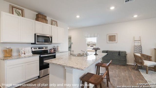 kitchen with a kitchen island with sink, appliances with stainless steel finishes, white cabinetry, and sink