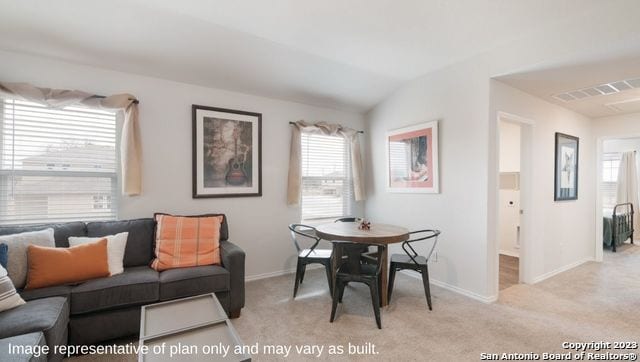 carpeted dining area featuring a wealth of natural light and vaulted ceiling