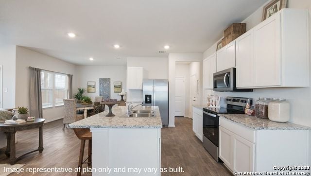 kitchen featuring stainless steel appliances, white cabinetry, dark hardwood / wood-style floors, sink, and an island with sink